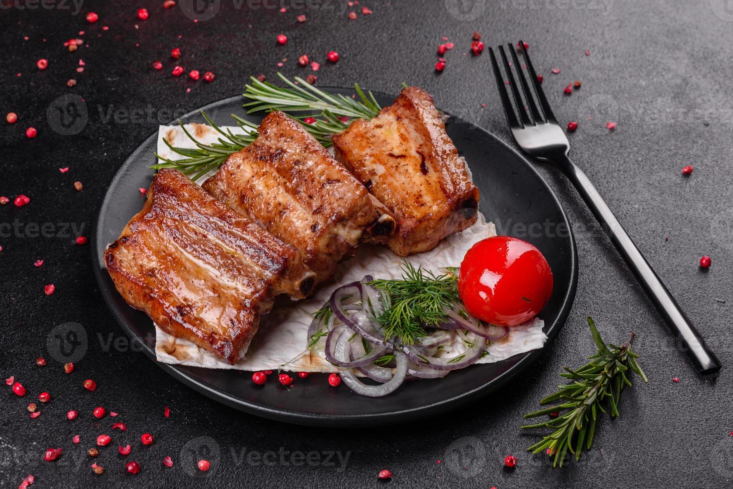 gebratene Rippchen mit Rosmarin, Zwiebeln, Sauce auf Betonuntergrund foto