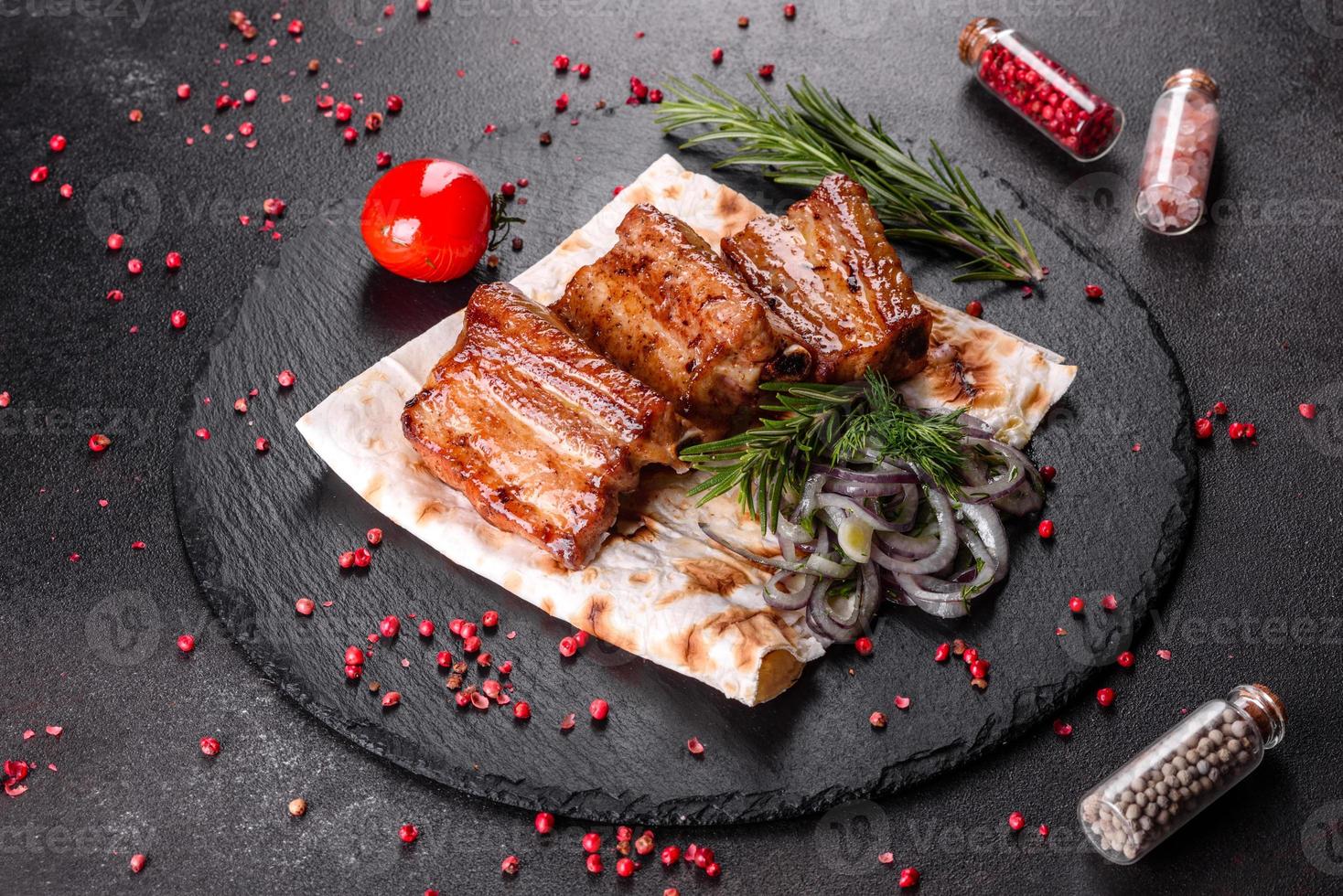 gebratene Rippchen mit Rosmarin, Zwiebeln, Sauce auf Betonuntergrund foto