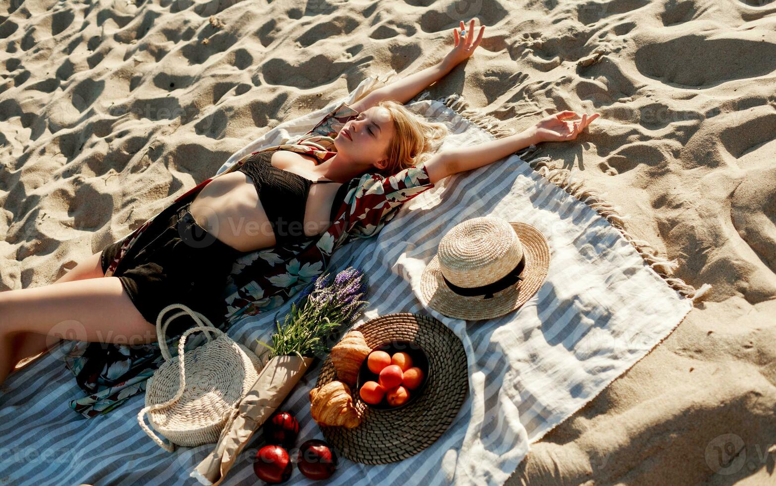 verführerisch blond Frau Lügen auf das Sand während Ausgaben Zeit auf Picknick auf das Strand. foto