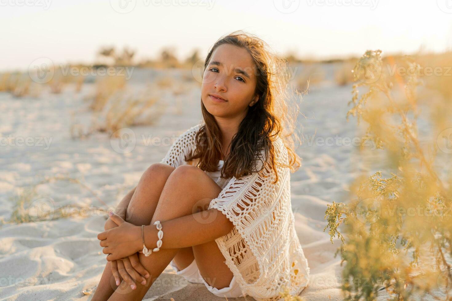 klein Mädchen im stilvoll Boho Sommer- Outfit posieren auf das Strand. warm Sonnenuntergang Farben. wacation und Reise Konzept. foto