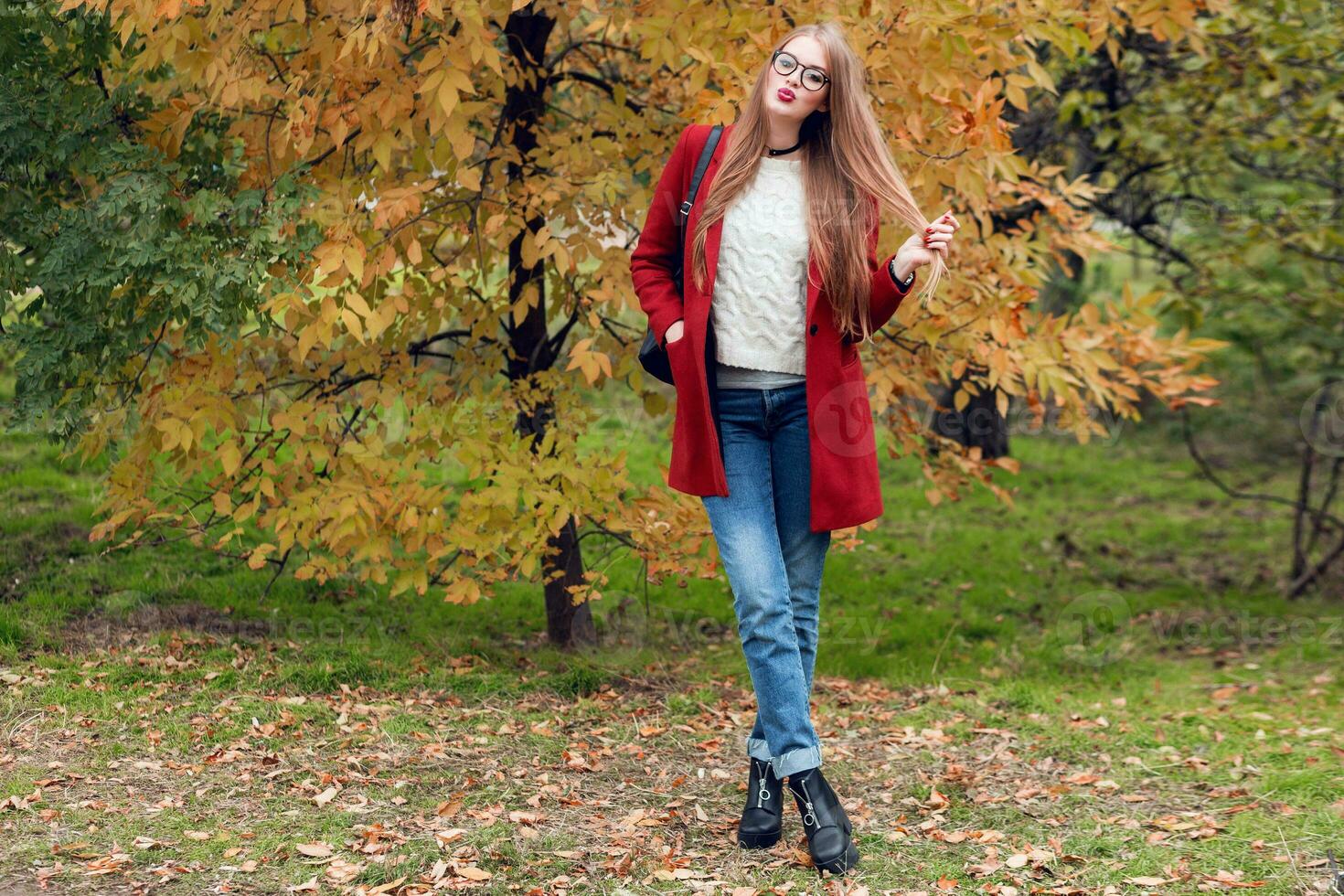 voll Höhe Herbst Mode Bild von nett Frau im rot stilvoll Mantel und gestrickt Hut im Herbst Park. foto