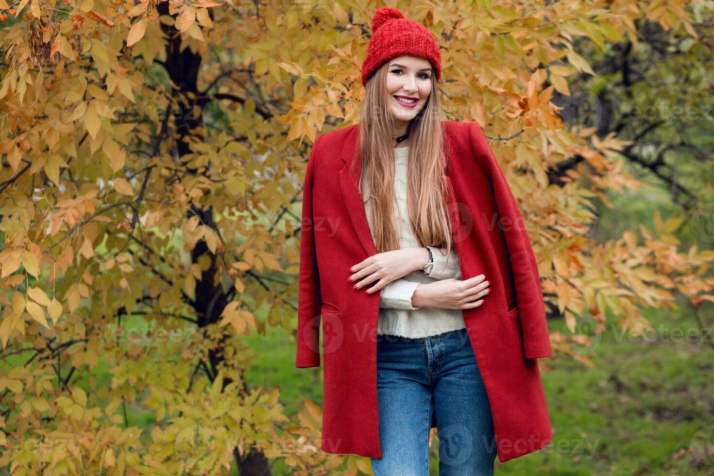 Herbst Mode Porträt von glücklich blond Frau im rot stilvoll Mantel und gestrickt Hut Gehen im Park. foto