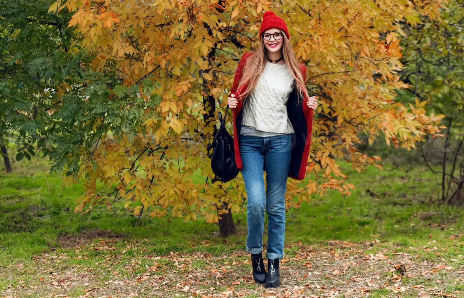 voll Höhe Herbst Mode Bild von ziemlich Frau im rot stilvoll Mantel und gestrickt Hut im Park. foto