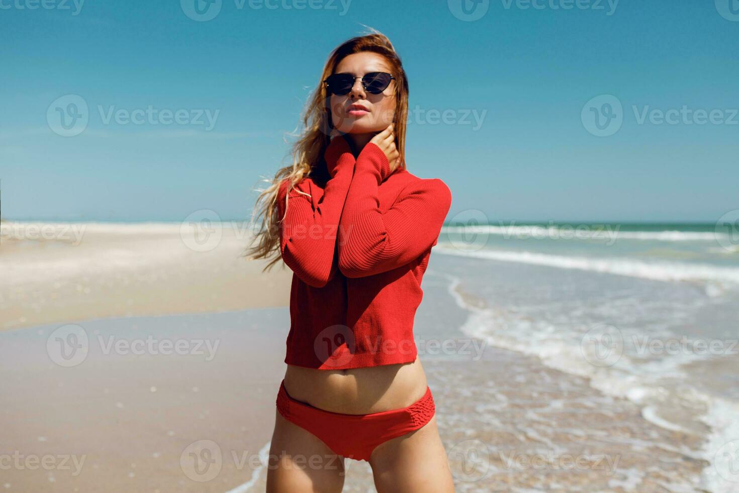 Ferien und Reise Konzept. Wunder blond Frau suchen auf das Ozean. tragen sexy rot Bikini. leeren Strand. tropisch Insel. perfekt Figur. foto