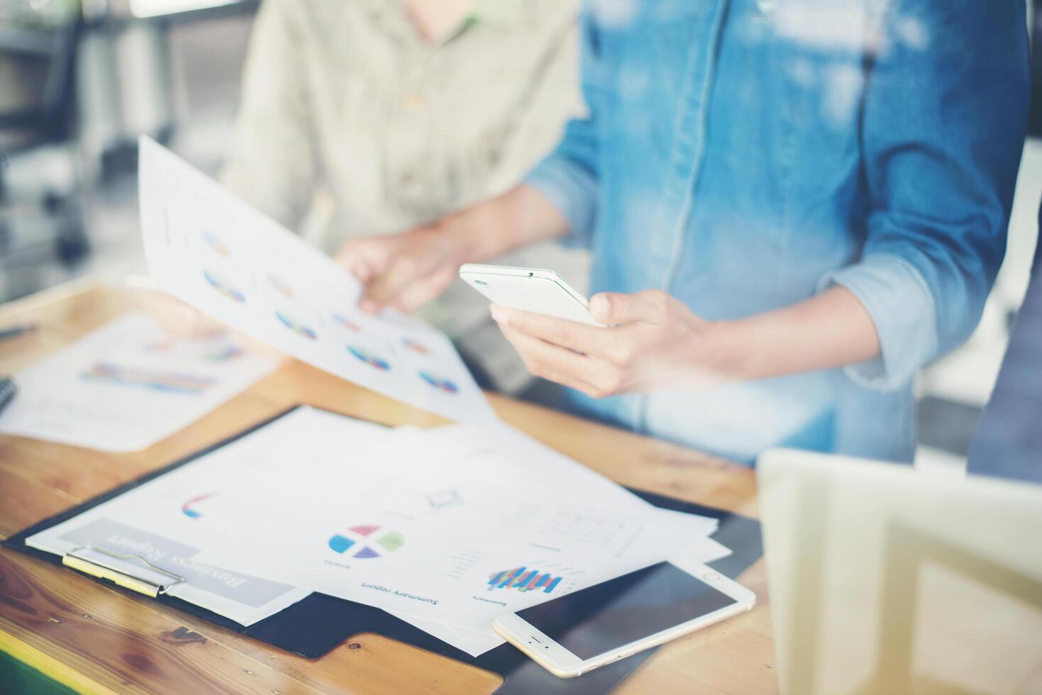 Die Hände einer Geschäftsfrau, die an Smartphones und Geschäftsinformationen arbeiten foto