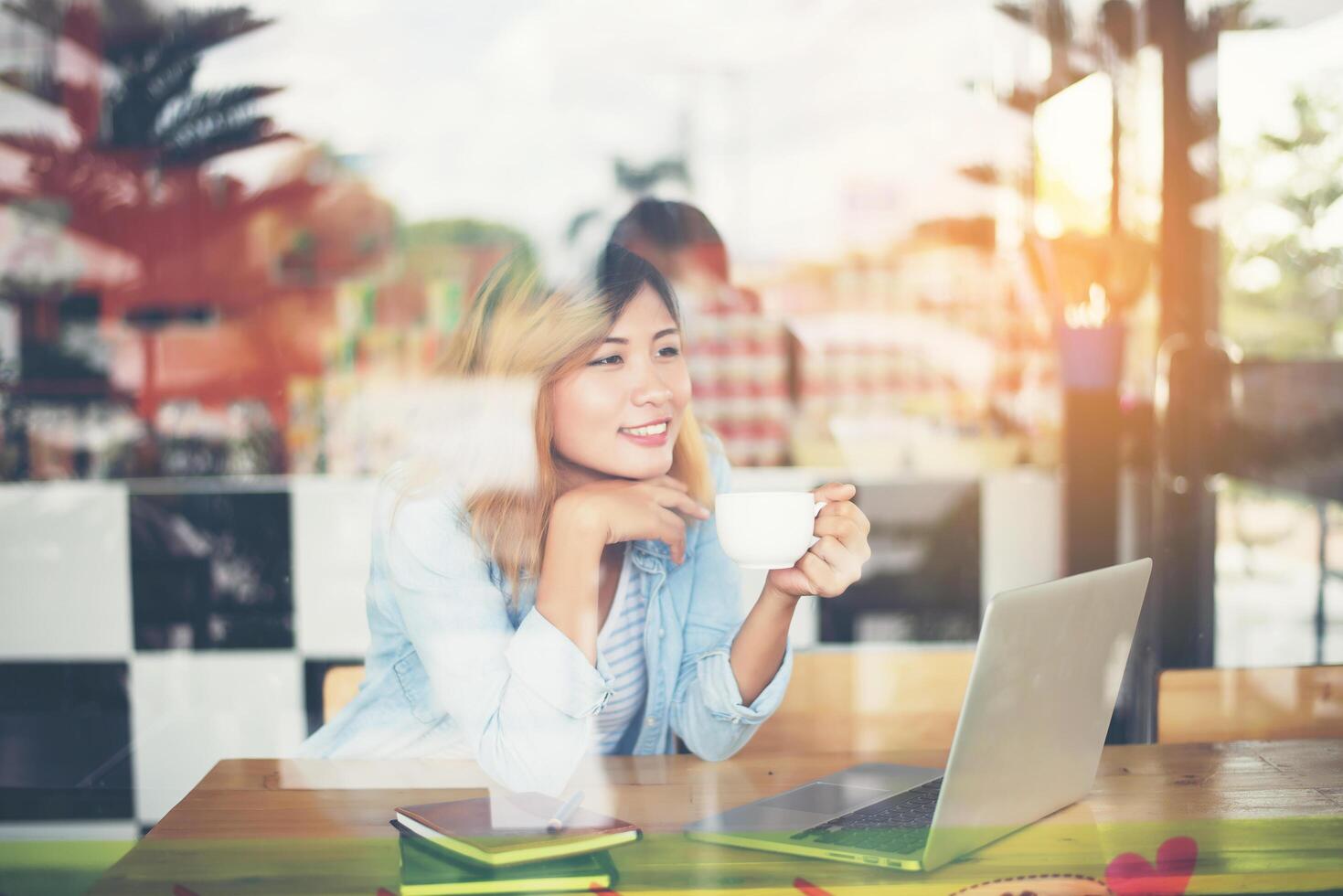 Junge schöne Hipster-Frau arbeitet im Café mit Fensterreflexion. foto