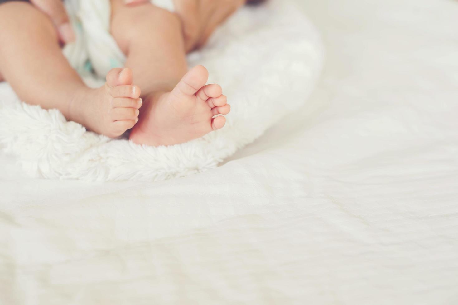 Neugeborene Babybeine auf weißem Bett. foto