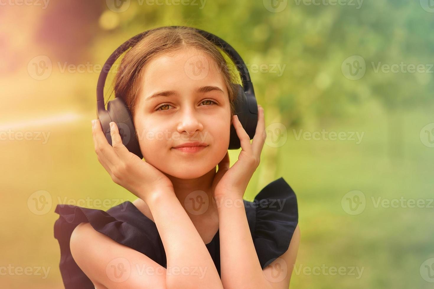 Schulmädchen im Park hört Musik mit Kopfhörern. foto