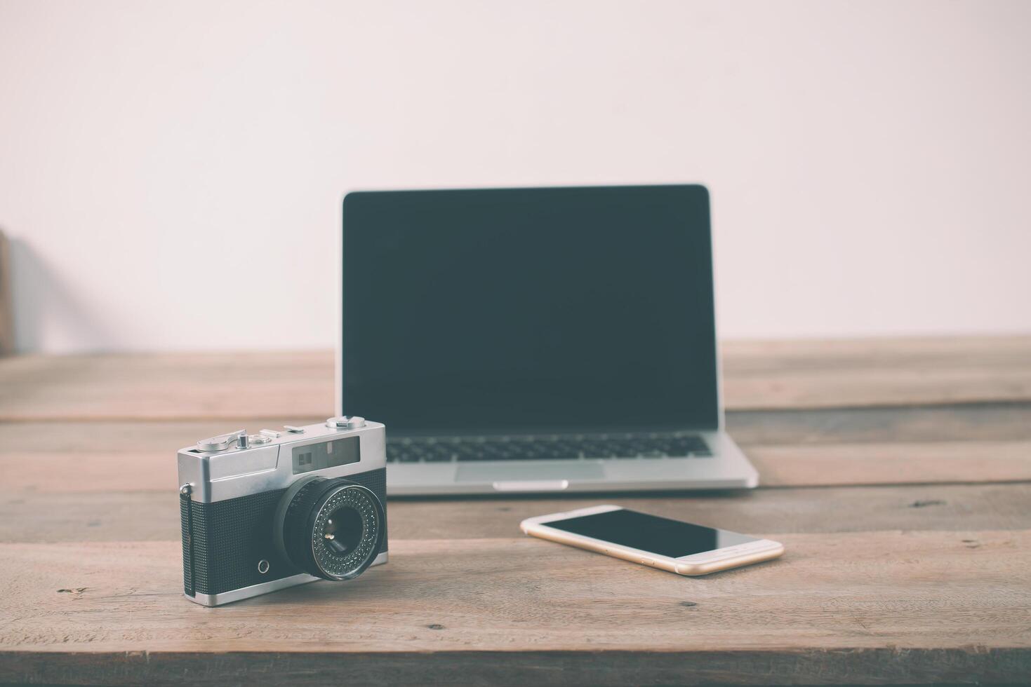 Holzarbeitstisch mit Laptop und Retro-Kamera arbeiten foto