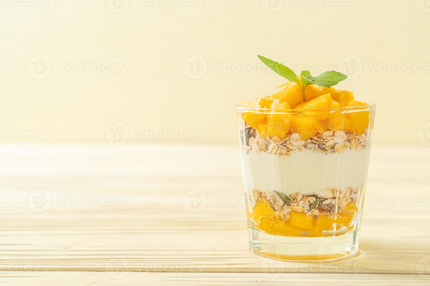 frischer Mangojoghurt mit Müsli im Glas - gesunder Food-Style foto