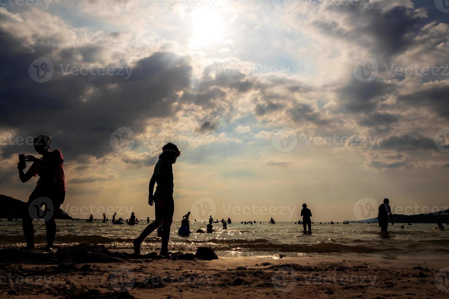 Silhouetten von Menschen, die an einem öffentlichen Strand im Meer spielen foto