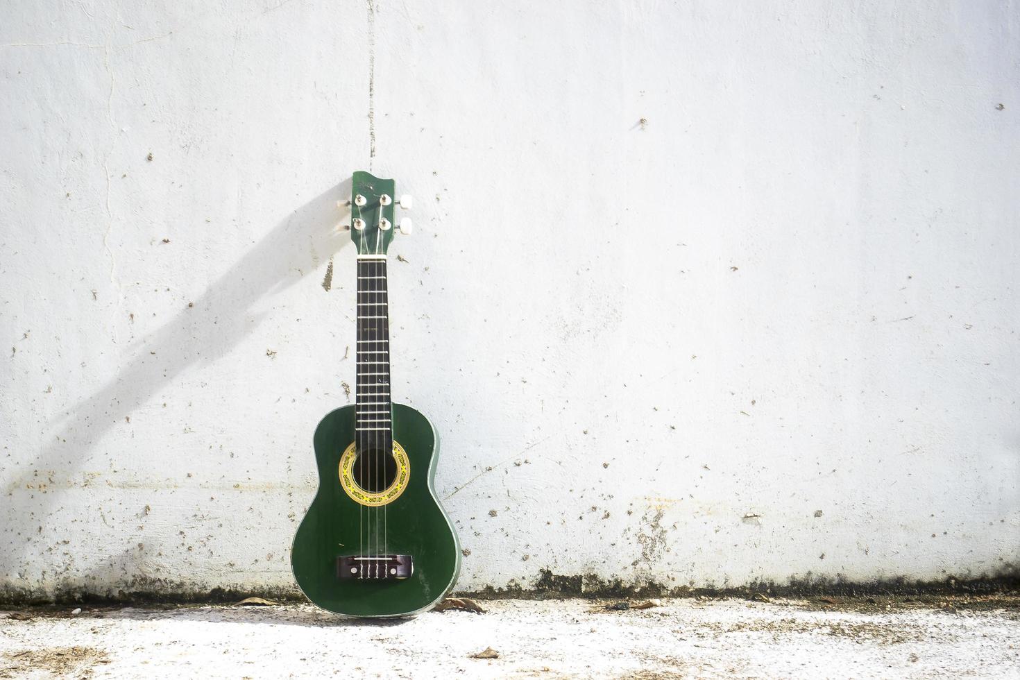 eine kleine Ukulele lehnt an einer weißen Wand foto