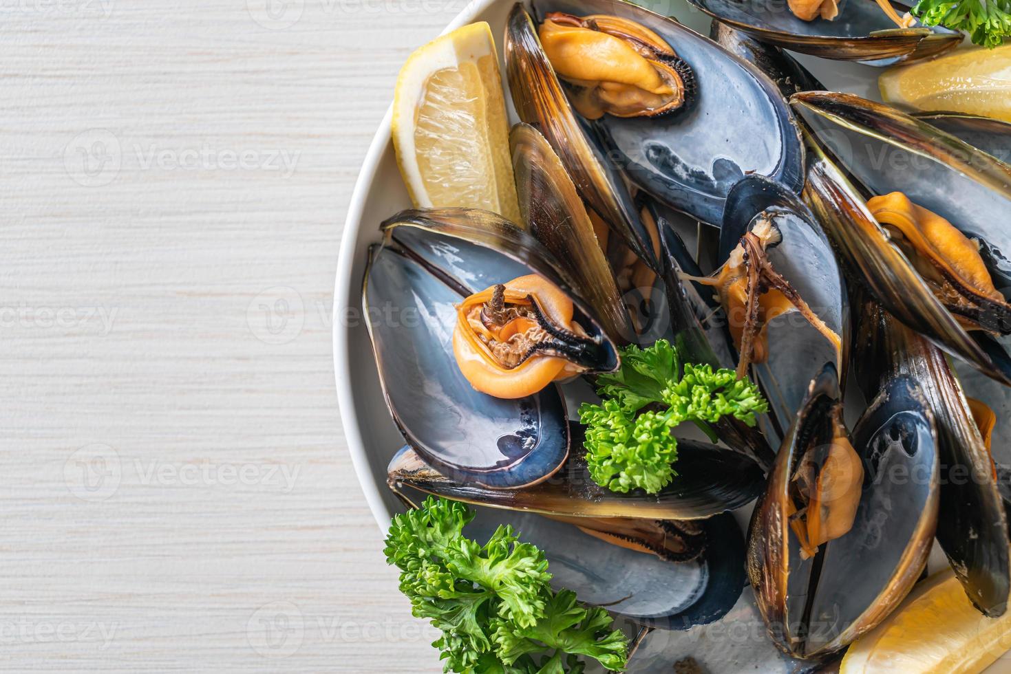 Muscheln mit Kräutern in einer Schüssel mit Zitrone foto