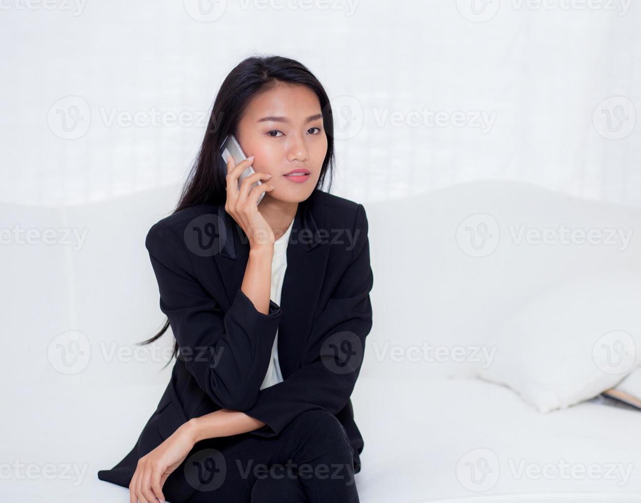 junge asiatische Frau, die im Wohnzimmer Smartphone spricht foto