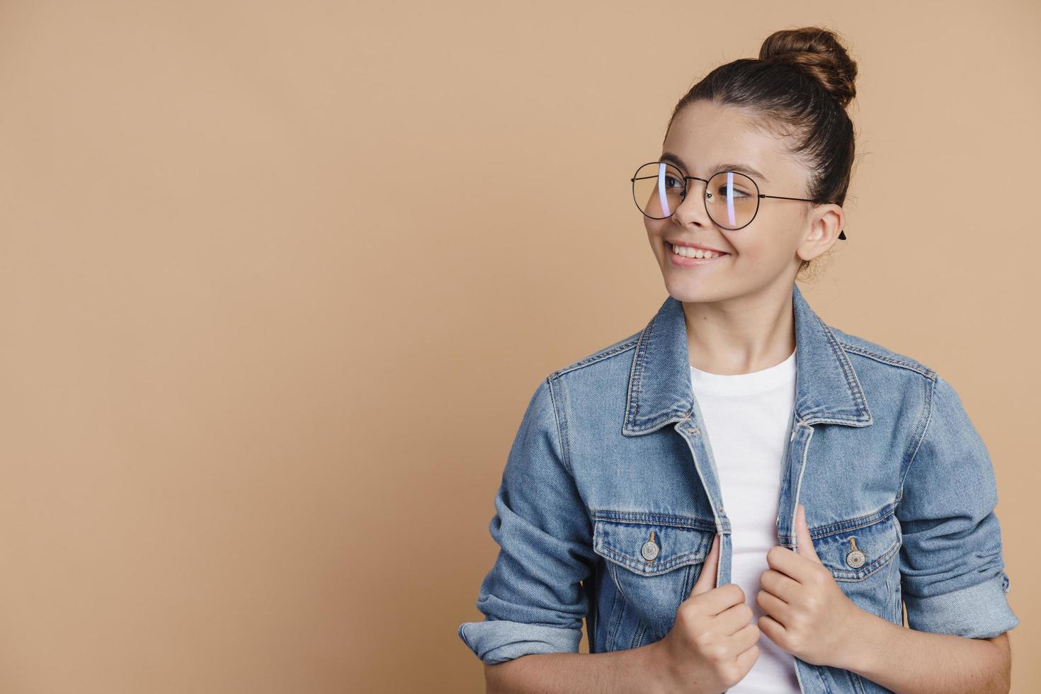 Teenager-Mädchen mit Brille posiert auf einem braunen Hintergrund foto