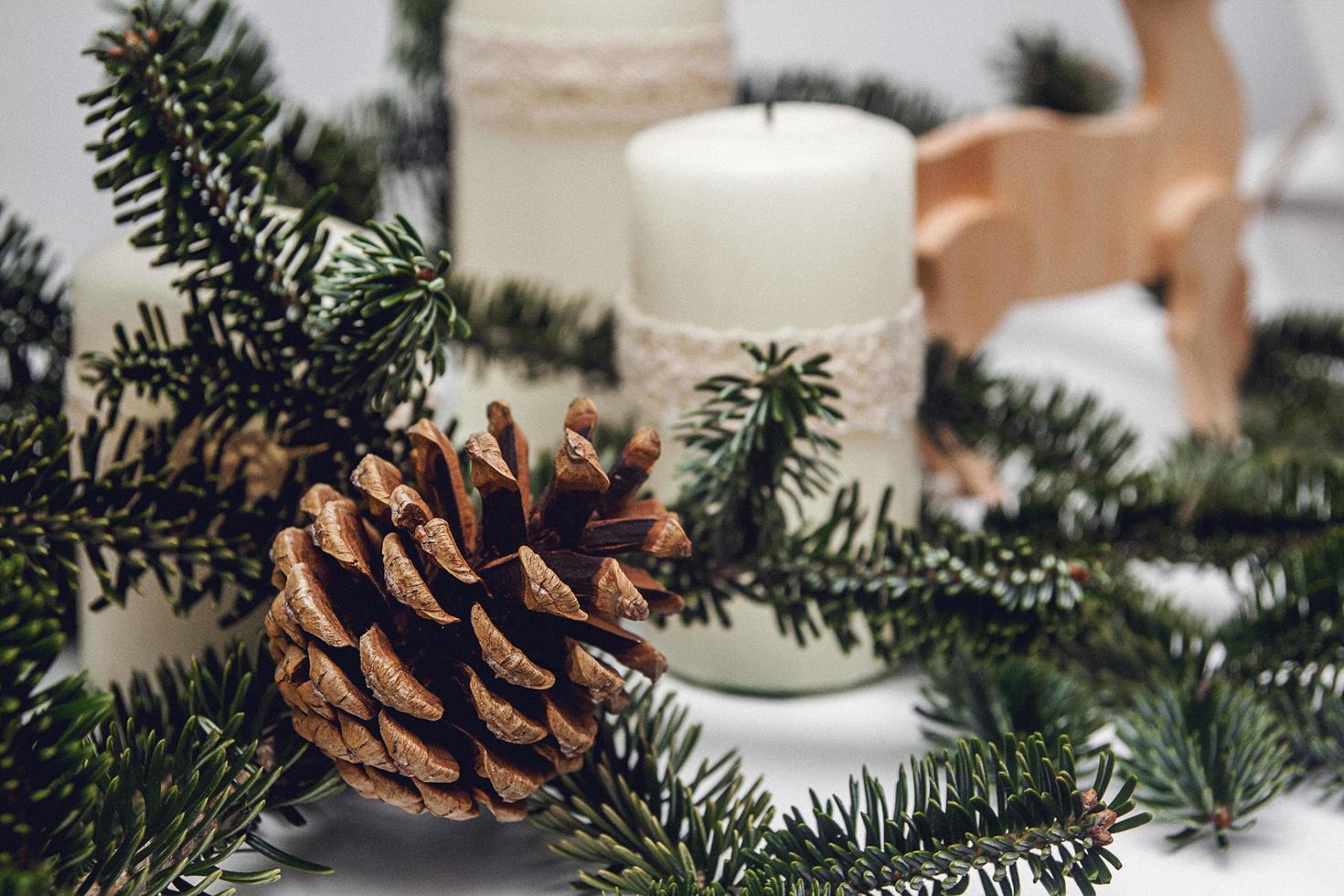 Drei Weihnachtskerzen, Kiefernzweig und Holzhirsch foto