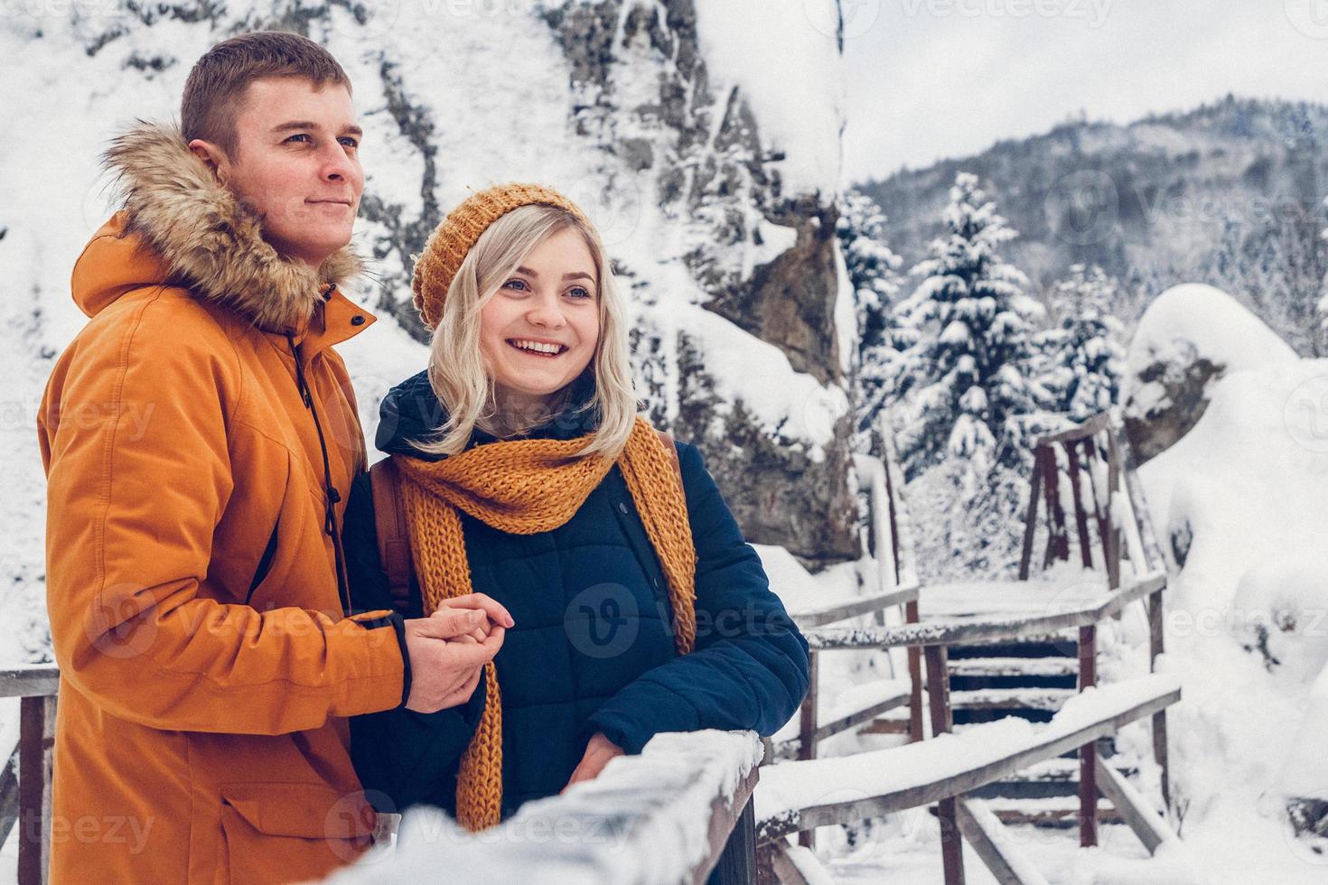 glückliches Liebespaar, das im Winterpark spazieren geht und Schnee genießt foto