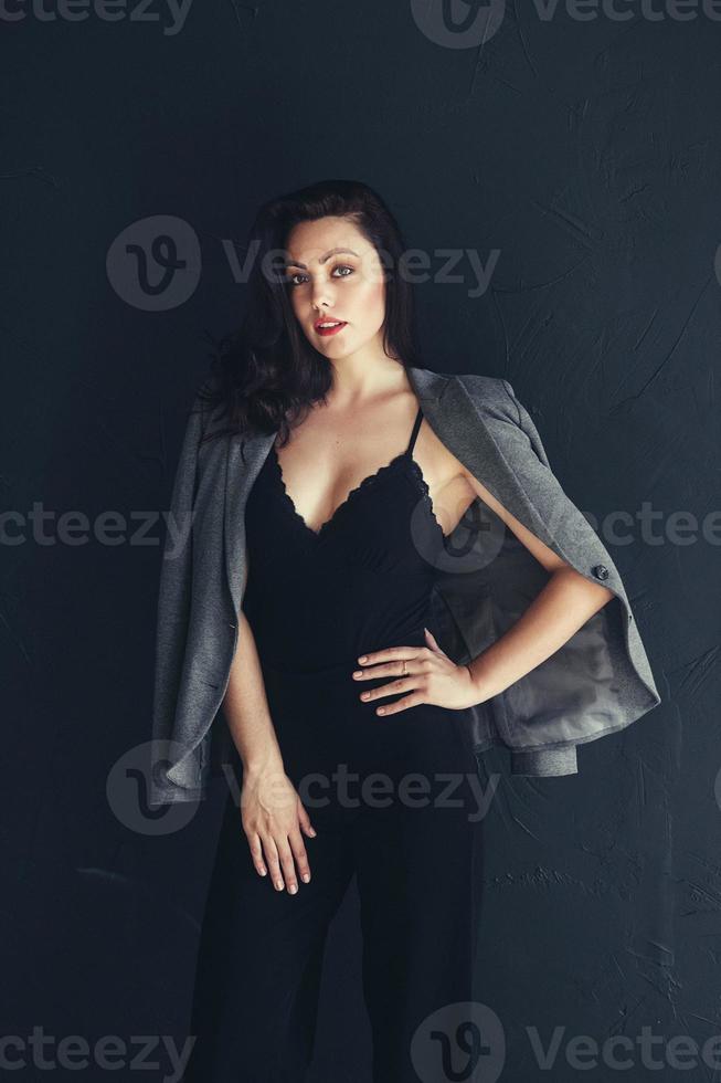 schöne Frau in lässiger dunkelgrauer Jacke auf schwarzem Hintergrund foto