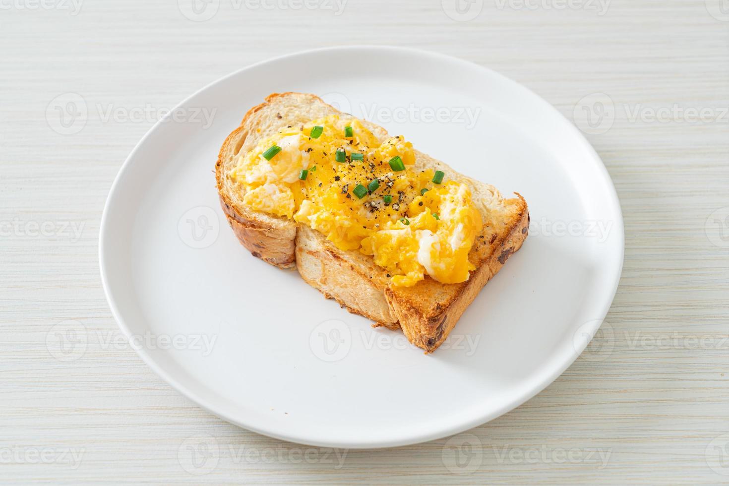 Brottoast mit Rührei auf weißem Teller foto
