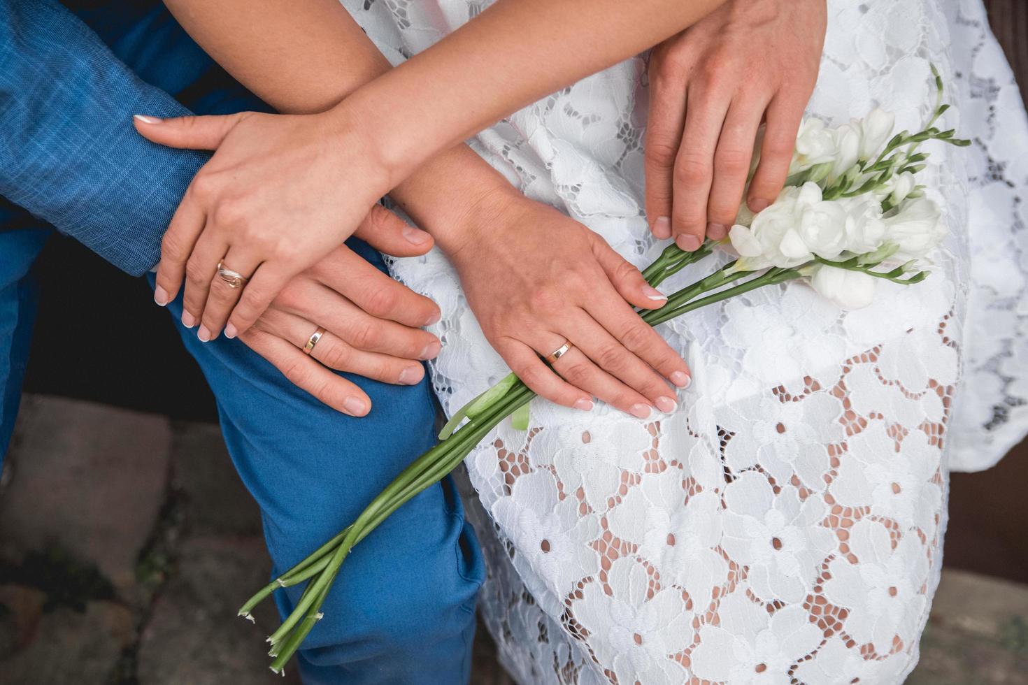 Hände des Brautpaares liegen auf einem Blumenstrauß foto