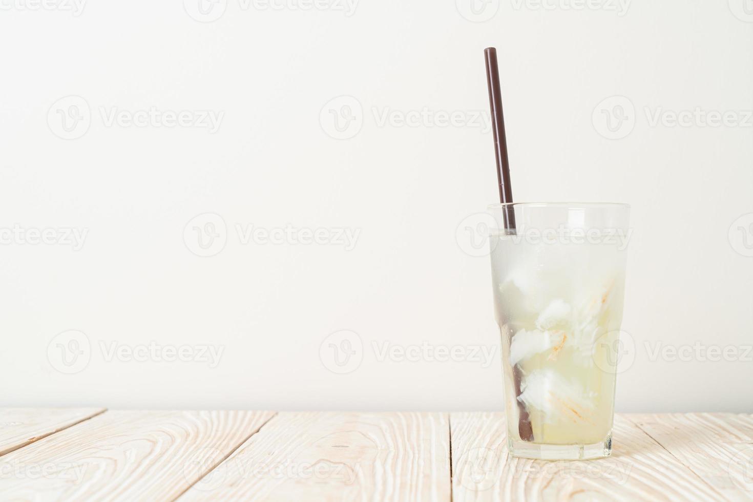 Kokoswasser oder Kokossaft im Glas mit Eiswürfel foto