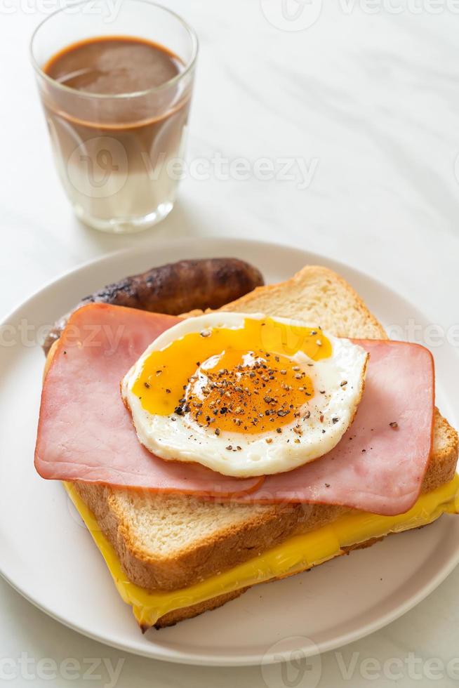 hausgemachtes Brot gerösteter Käse überbackener Schinken und Spiegelei mit Schweinswurst und Kaffee zum Frühstück foto