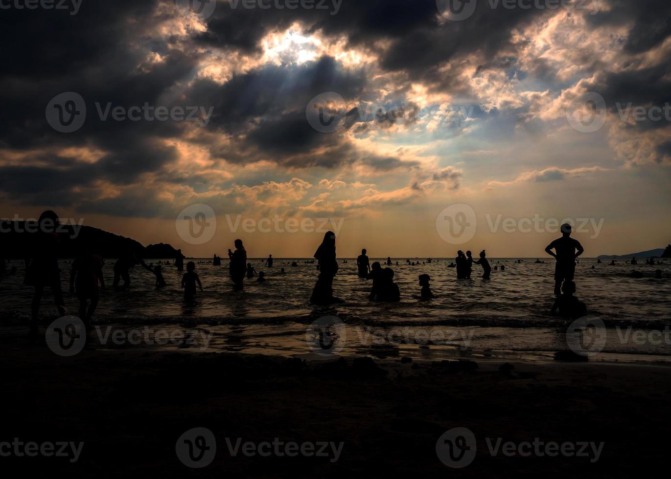 Silhouetten von Menschen, die an einem öffentlichen Strand im Meer spielen foto