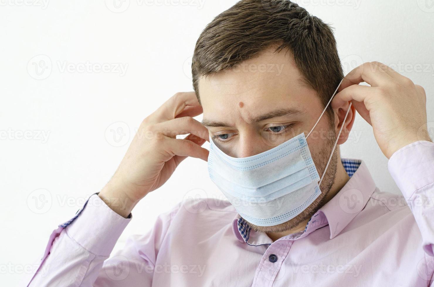 Ein Mann im Hemd setzt eine Maske auf. Virus Schutz. foto