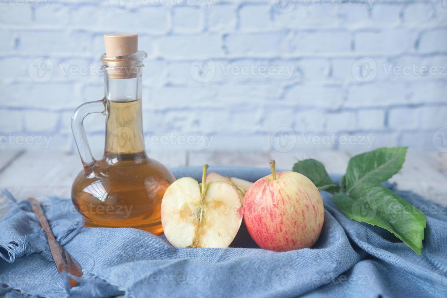 Apfelessig in Glasflasche mit frischem grünem Apfel auf dem Tisch foto