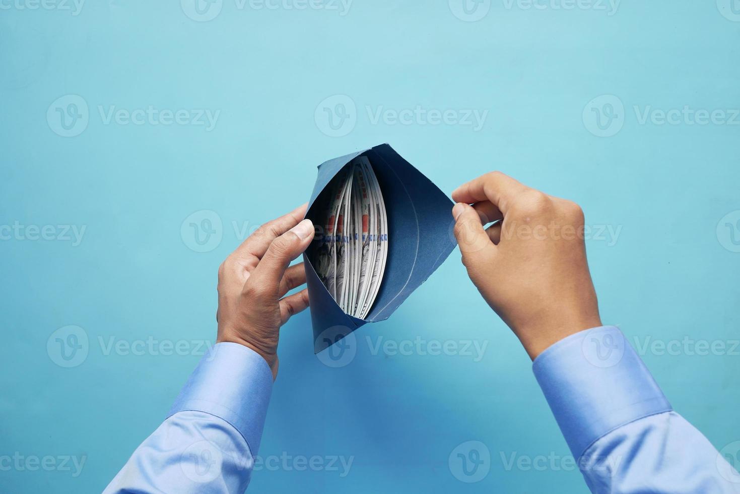 Personenhand, die Bargeld in einen Umschlag steckt. foto