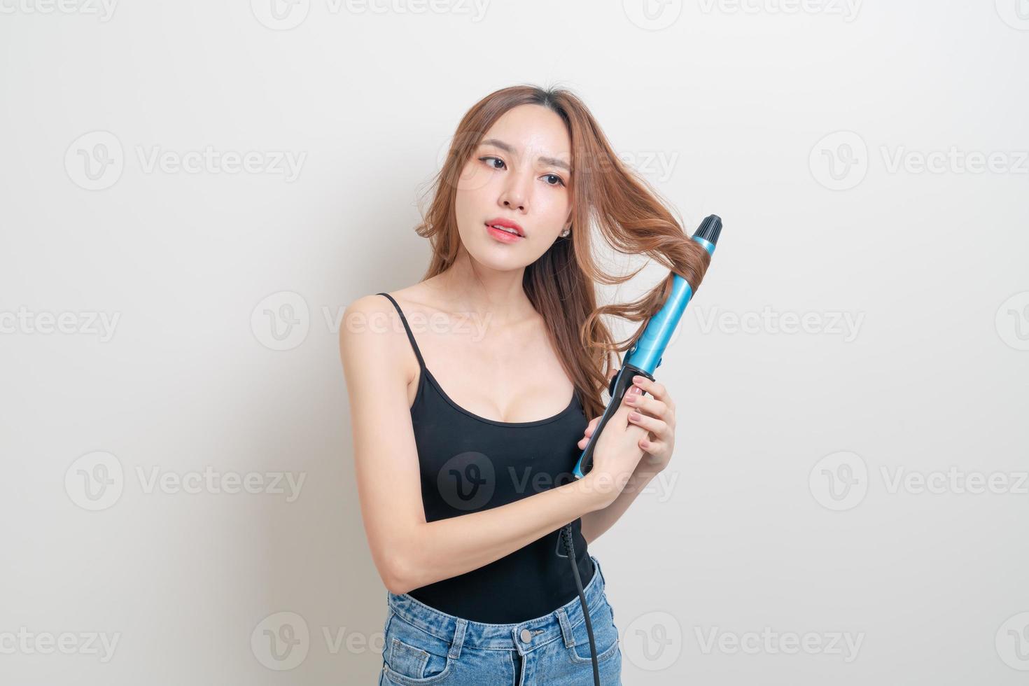 Porträt schöne asiatische Frau mit Lockenwickler oder Lockenstab auf weißem Hintergrund foto