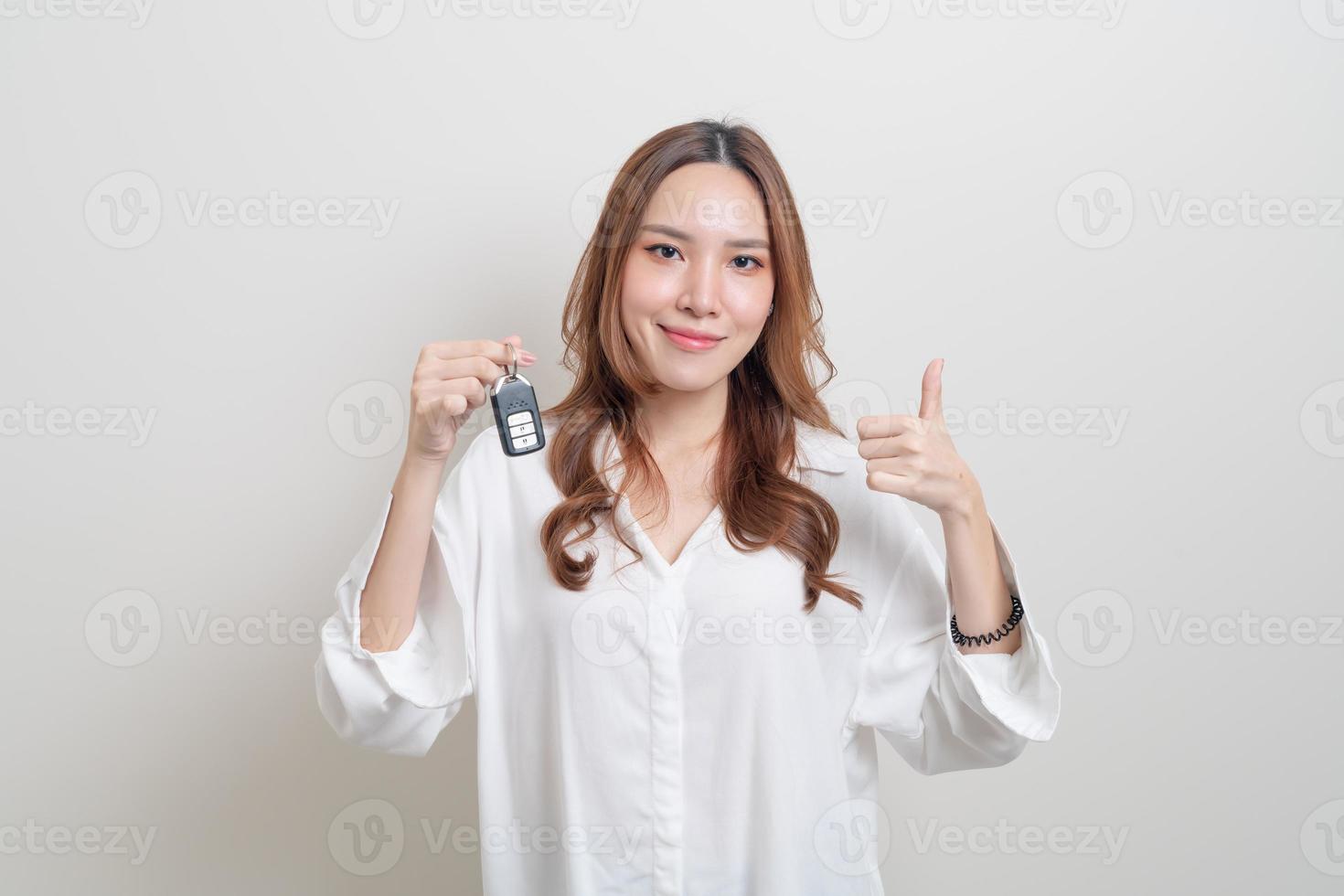 Porträt schöne asiatische Frau mit Autoschlüssel auf weißem Hintergrund foto