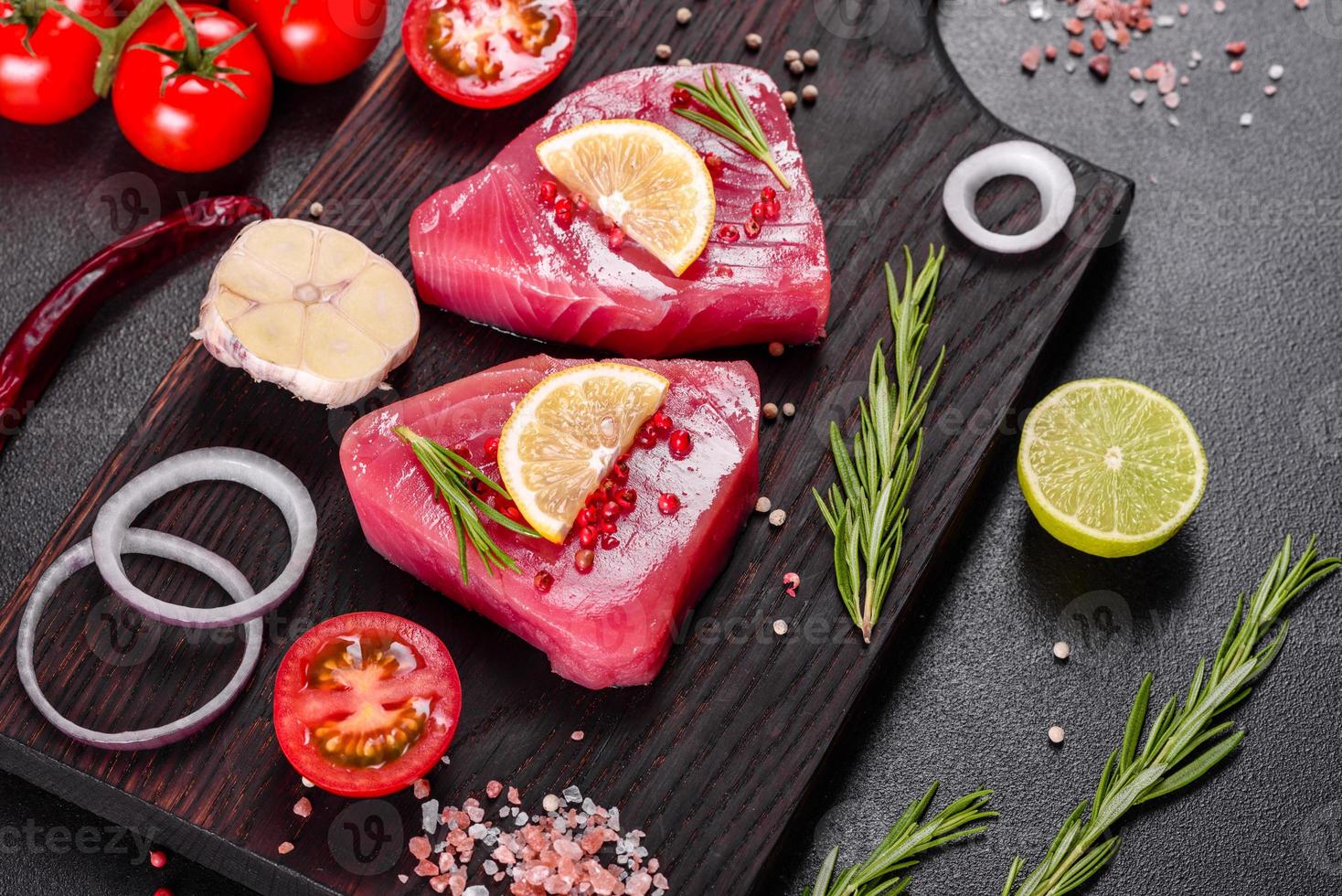 frische Thunfischfiletsteaks mit Gewürzen und Kräutern auf schwarzem Hintergrund foto