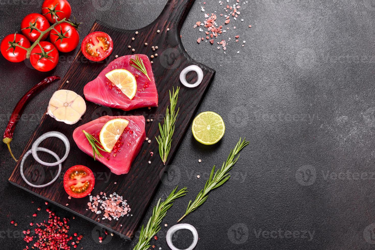 frische Thunfischfiletsteaks mit Gewürzen und Kräutern auf schwarzem Hintergrund foto