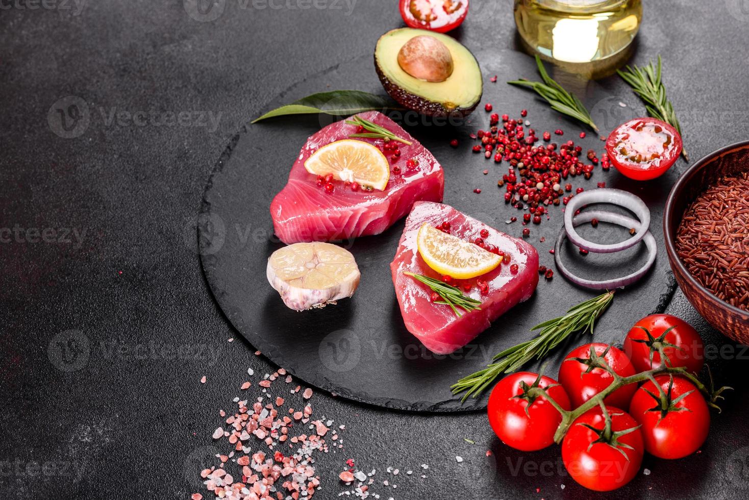 frische Thunfischfiletsteaks mit Gewürzen und Kräutern auf schwarzem Hintergrund foto