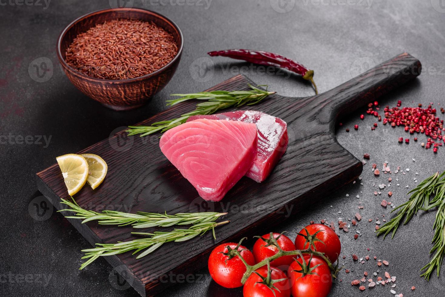 frische Thunfischfiletsteaks mit Gewürzen und Kräutern auf schwarzem Hintergrund foto