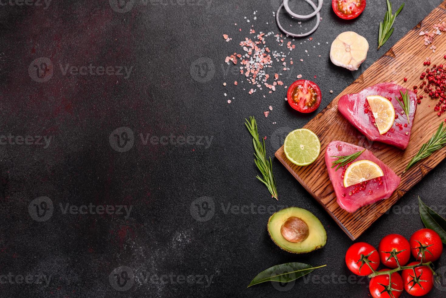 frische Thunfischfiletsteaks mit Gewürzen und Kräutern auf schwarzem Hintergrund foto