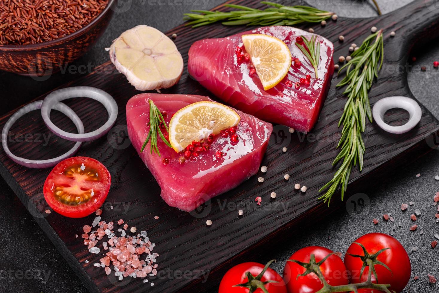 frische Thunfischfiletsteaks mit Gewürzen und Kräutern auf schwarzem Hintergrund foto