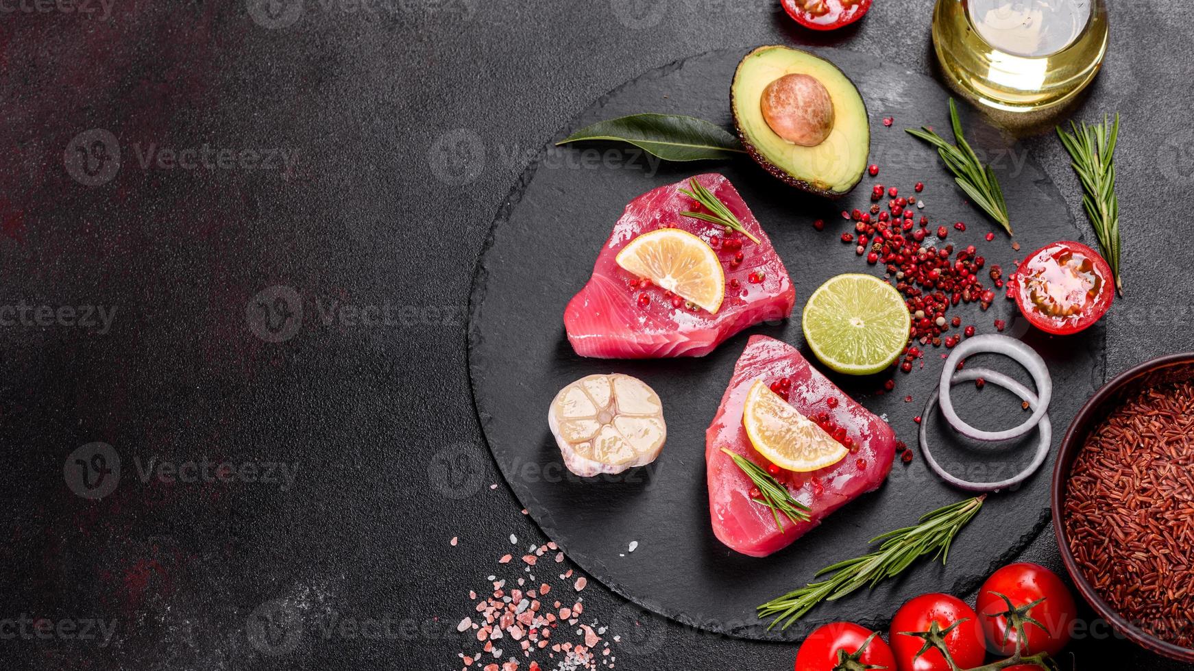 frische Thunfischfiletsteaks mit Gewürzen und Kräutern auf schwarzem Hintergrund foto