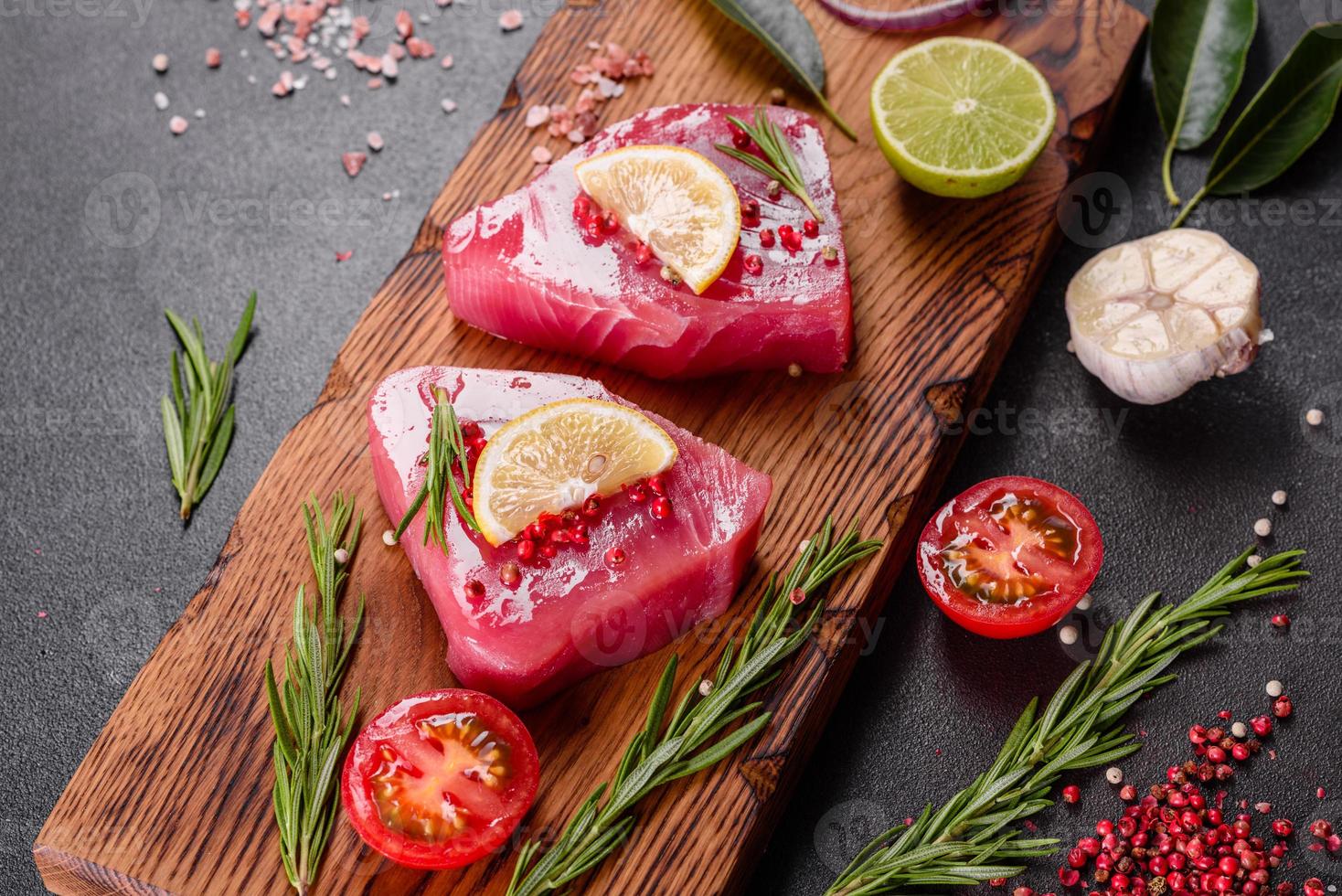 frische Thunfischfiletsteaks mit Gewürzen und Kräutern auf schwarzem Hintergrund foto