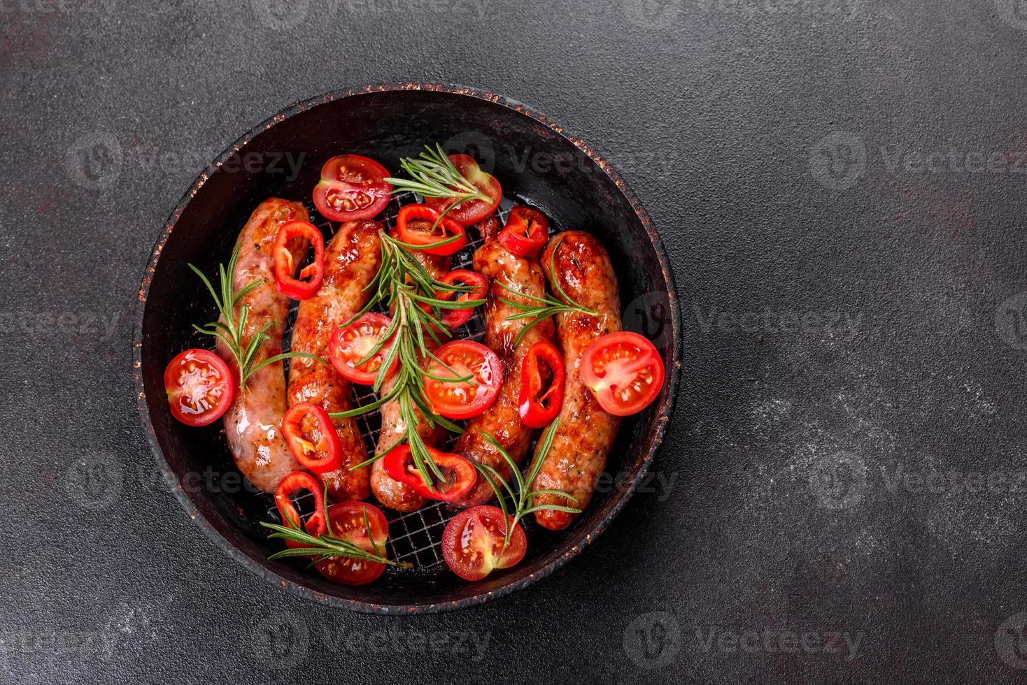 gegrillte Würstchen mit Gemüse und Gewürzen auf schwarzem Hintergrund foto