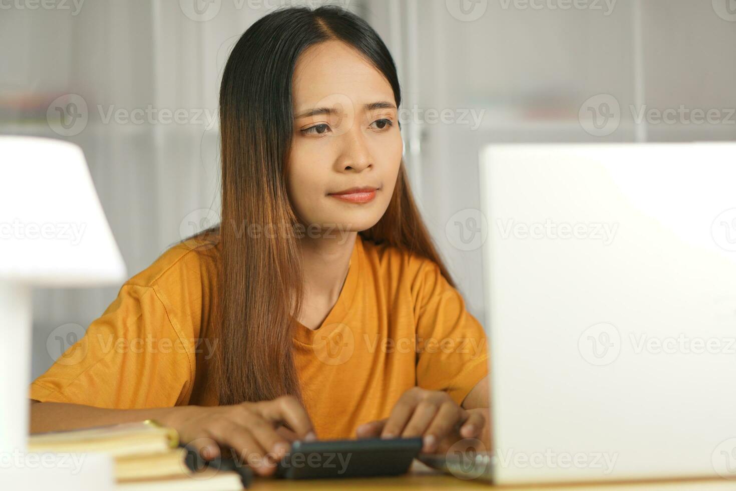 asiatisch Frauen Drücken Sie zu Arbeit von Zuhause klicken auf das Taschenrechner zu sehen Gewinne. foto