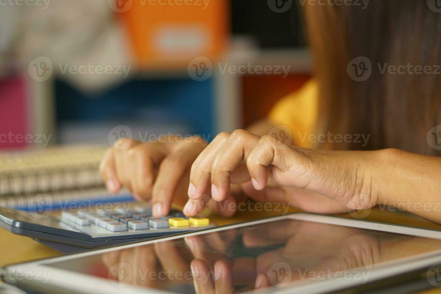 asiatisch Frauen Drücken Sie zu Arbeit von Zuhause klicken auf das Taschenrechner zu sehen Gewinne. foto