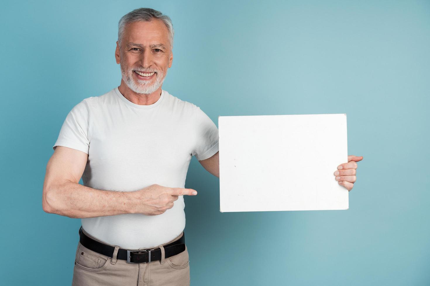 lächelnder, angenehmer, älterer Mann hält ein weißes Blatt Papier foto