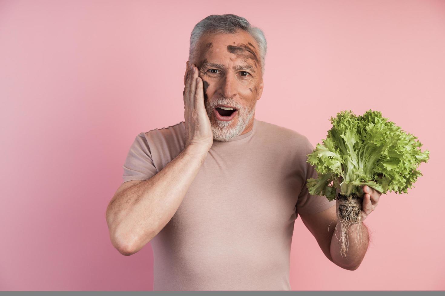 Attraktiver, überraschter älterer Mann, der einen Haufen frisch hält foto