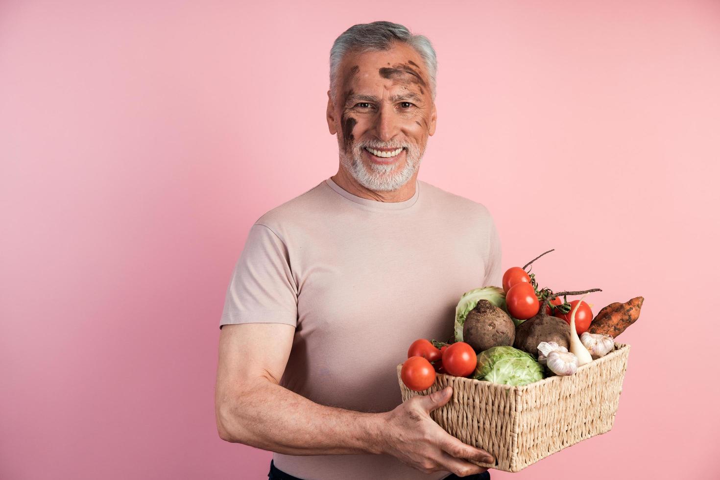 älterer Mann hält sich nützlich mit selbst angebauten Produkten, die auf organischem Boden angebaut werden foto