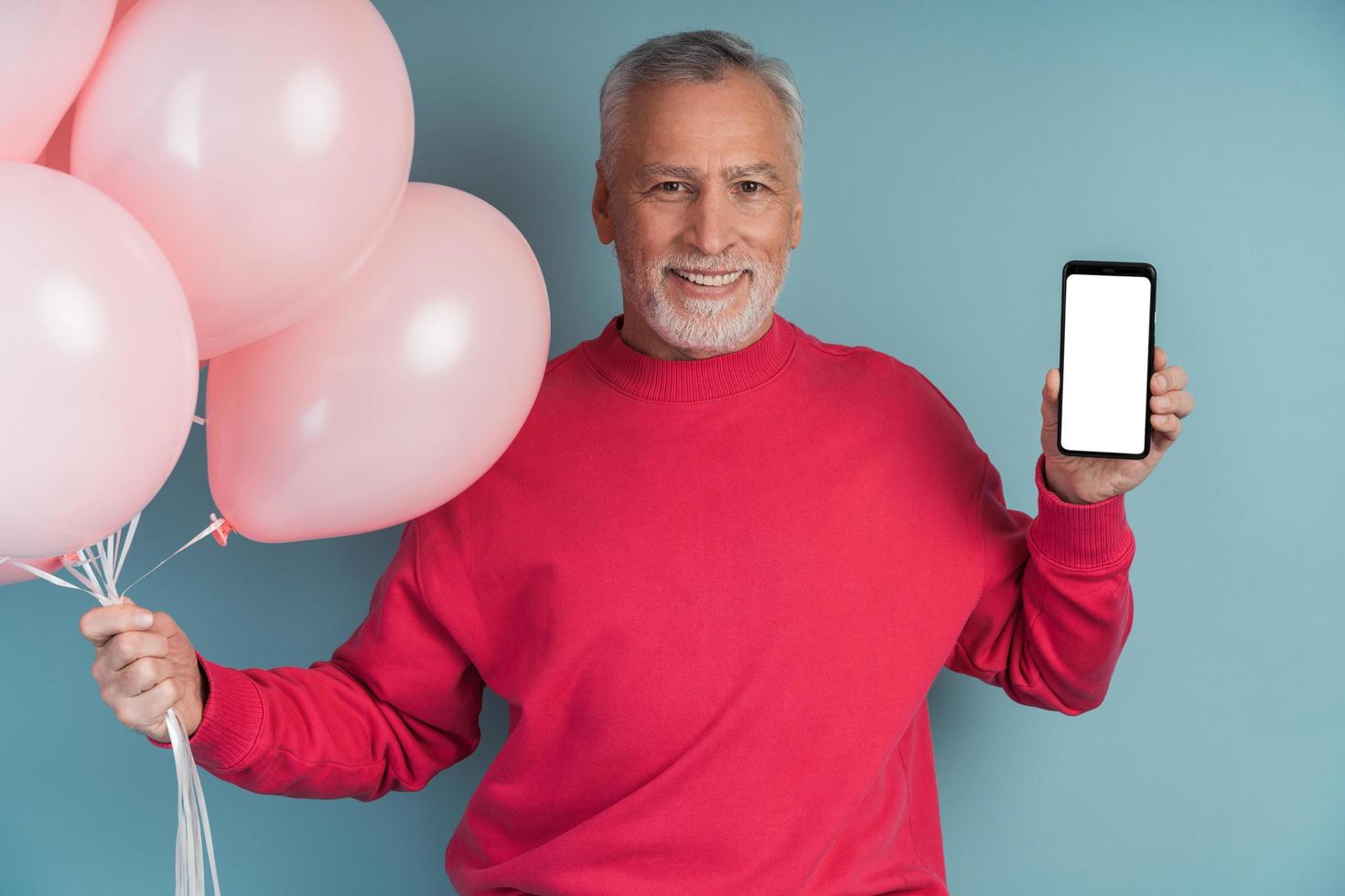 Mann mit Luftballons mit hellem Pullover posiert auf blauem Hintergrund foto