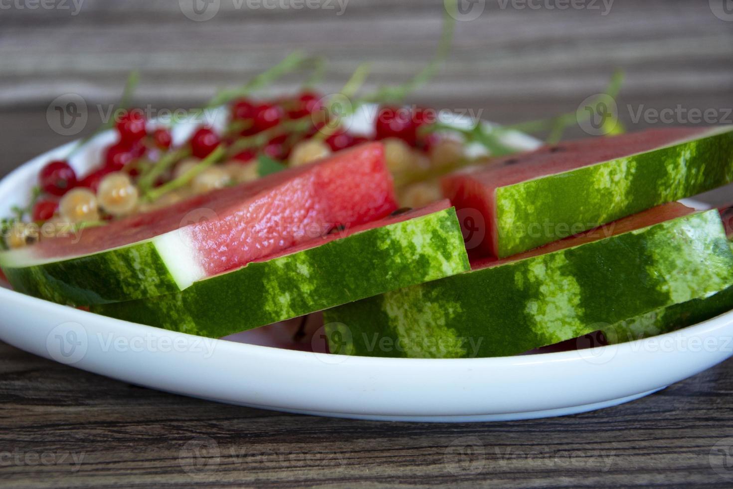 Wassermelone und Johannisbeeren auf einem Holzplan foto