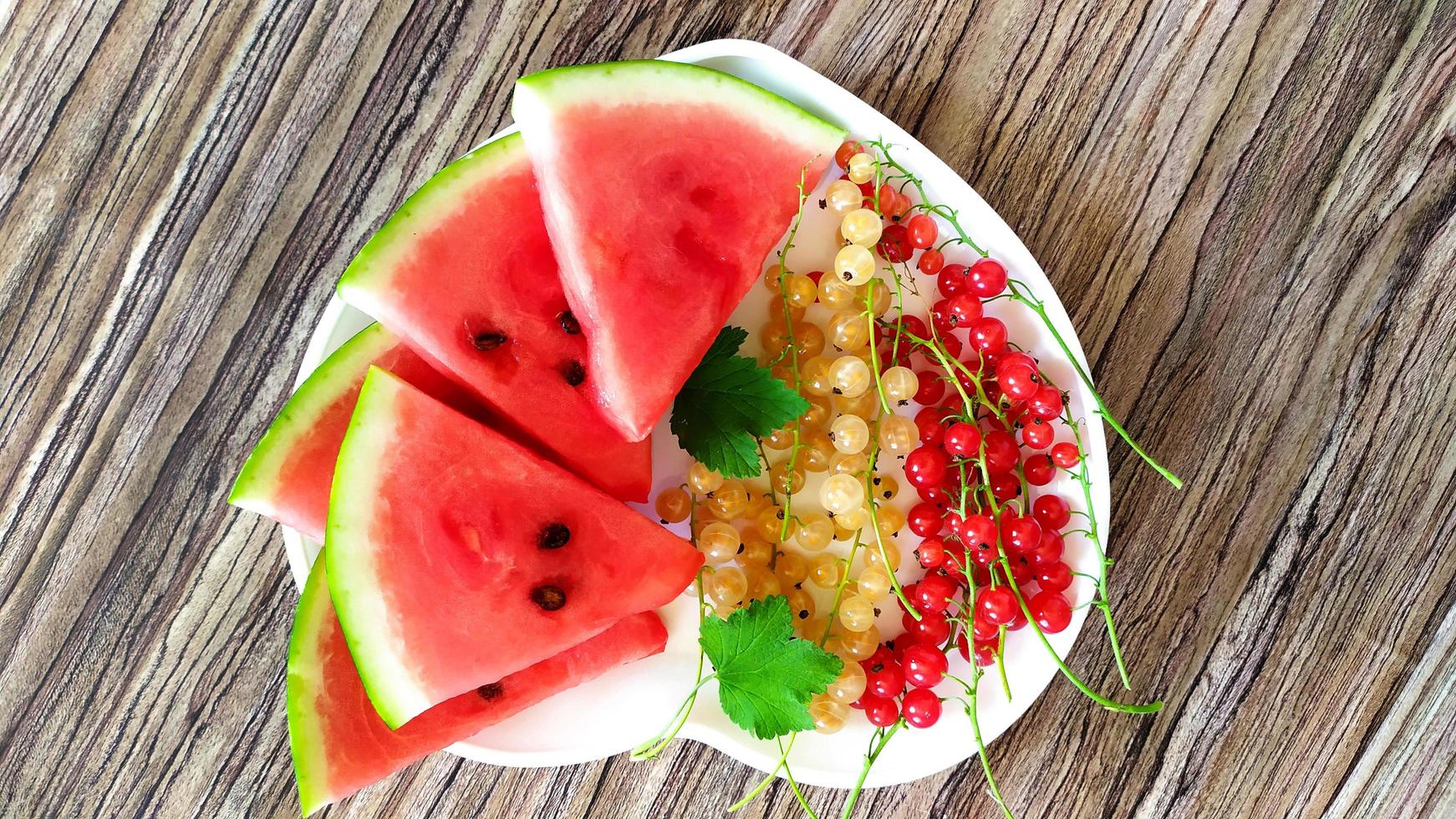 Scheiben von Wassermelone und Johannisbeeren liegen auf einem Teller foto