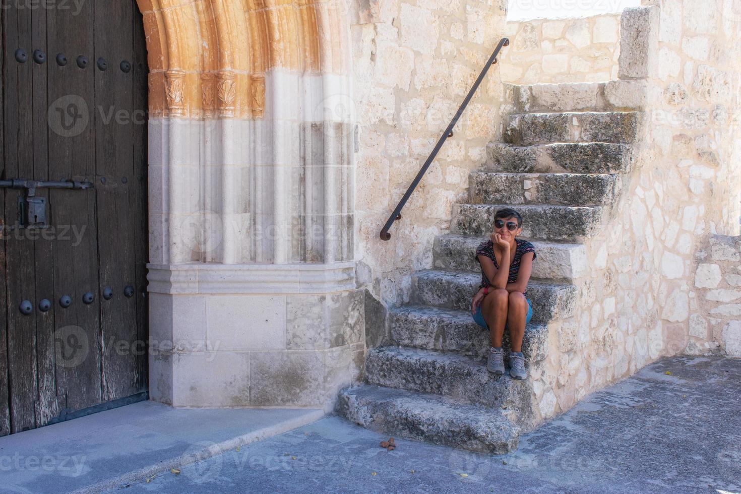 Frau sitzt auf der Treppe einer mittelalterlichen Kirche foto